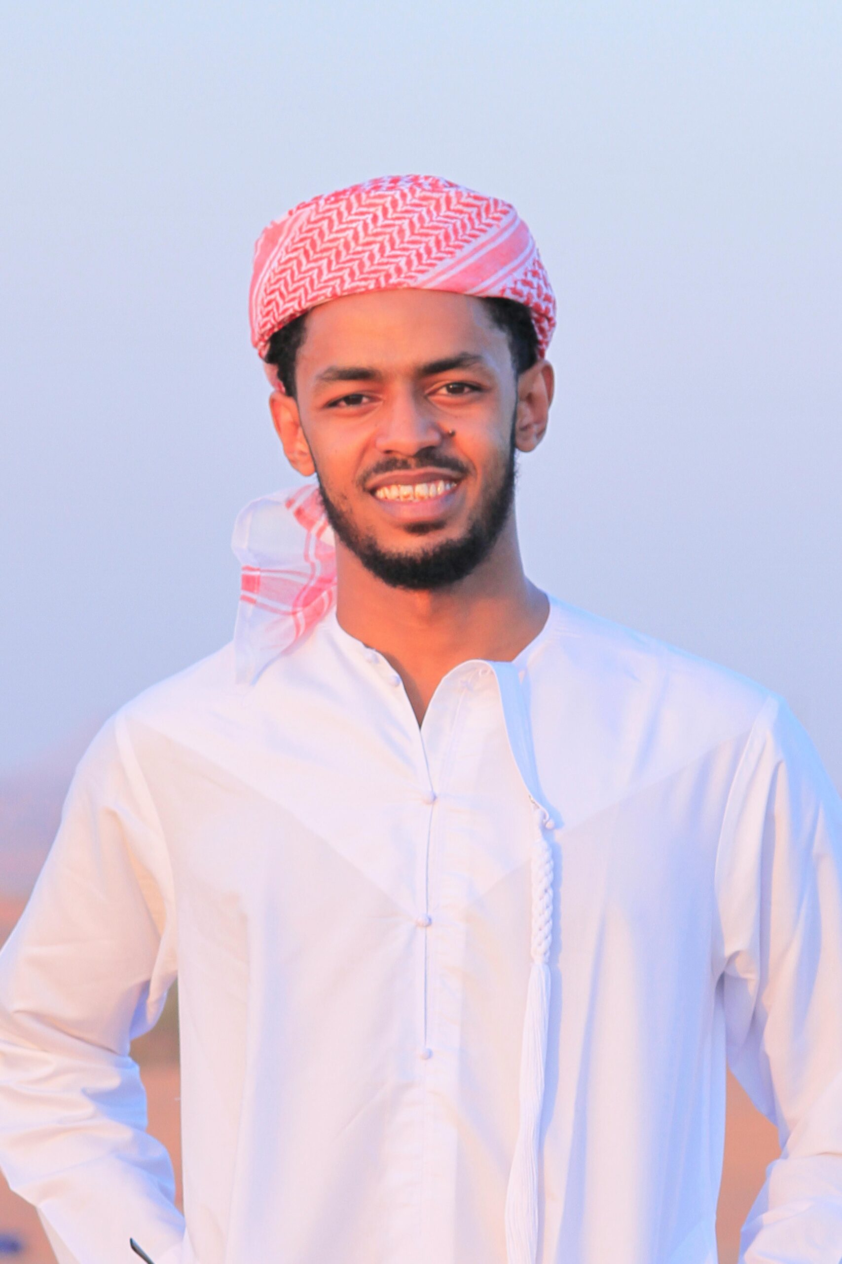 Home Portrait of a smiling young Middle Eastern man wearing traditional clothing outdoors.